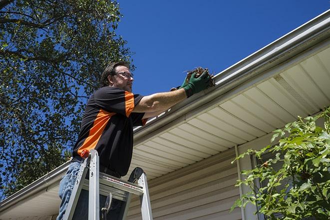 a worker using tools to fix a broken gutter in Grafton